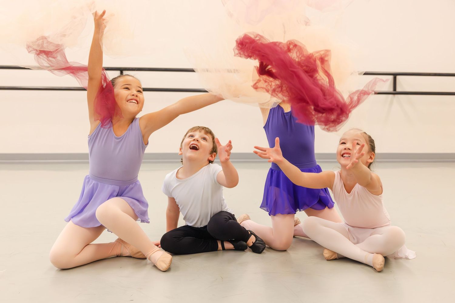 Young dance students in ballet attire having fun and laughing during dance class in a studio.