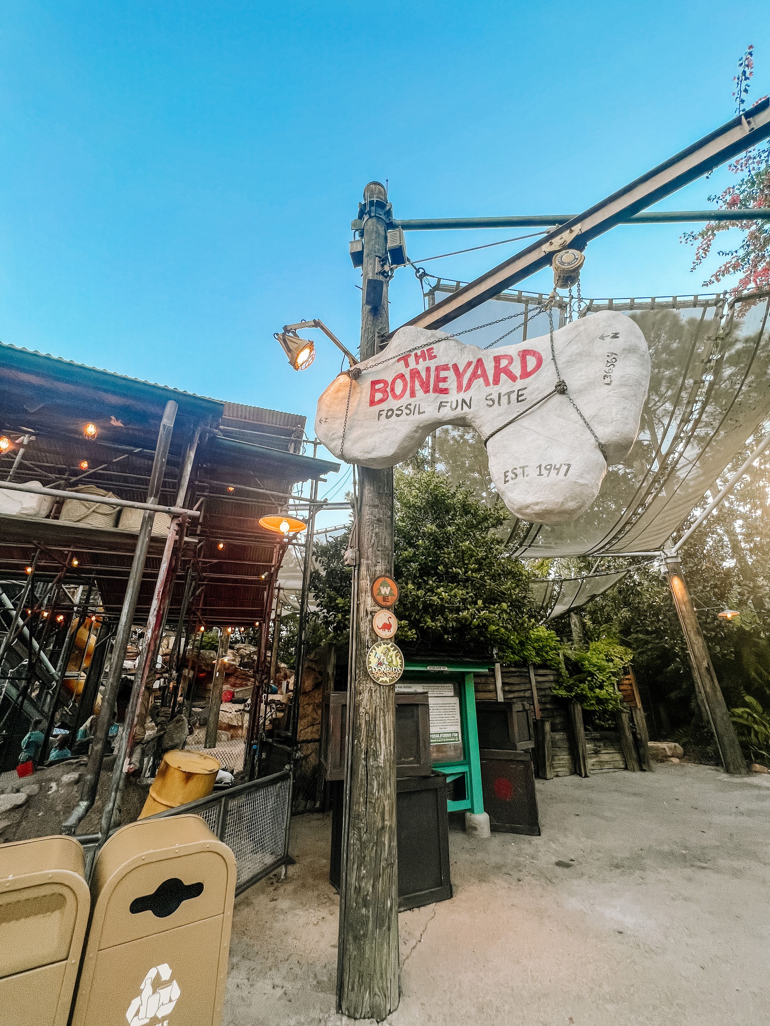 Vintage sign for The Boneyard restaurant on a utility pole with outdoor seating and string lights visible at dusk.