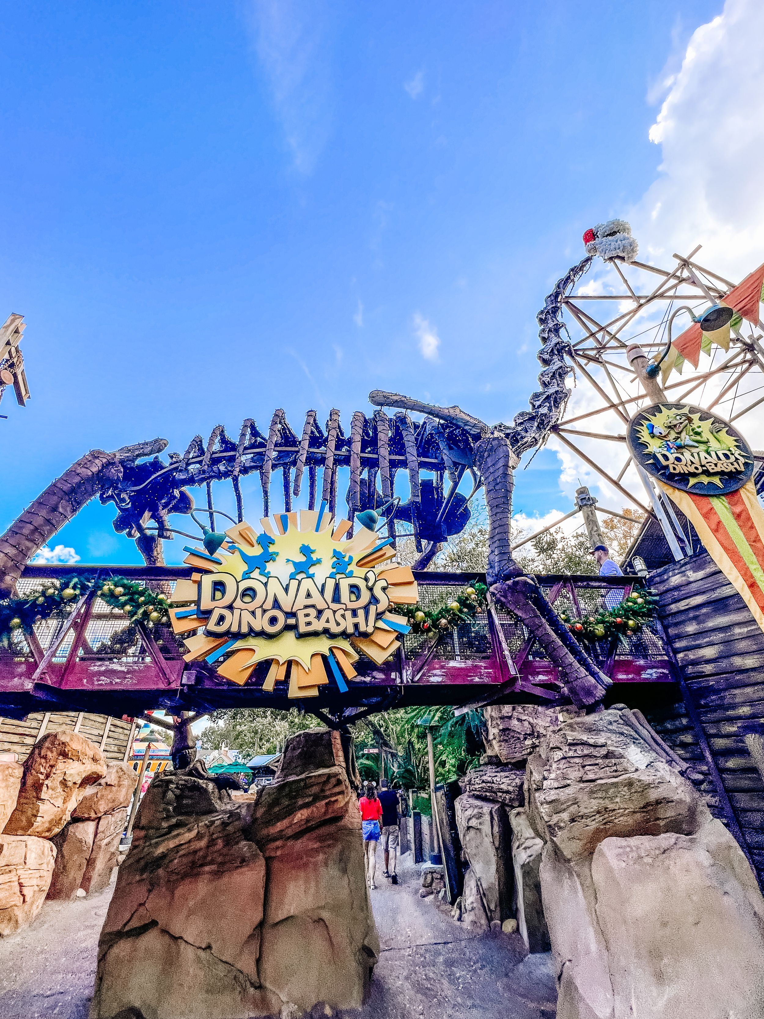 The entrance to DinoLand USA attraction at Disney's Animal Kingdom features a large blue dinosaur skeleton archway.