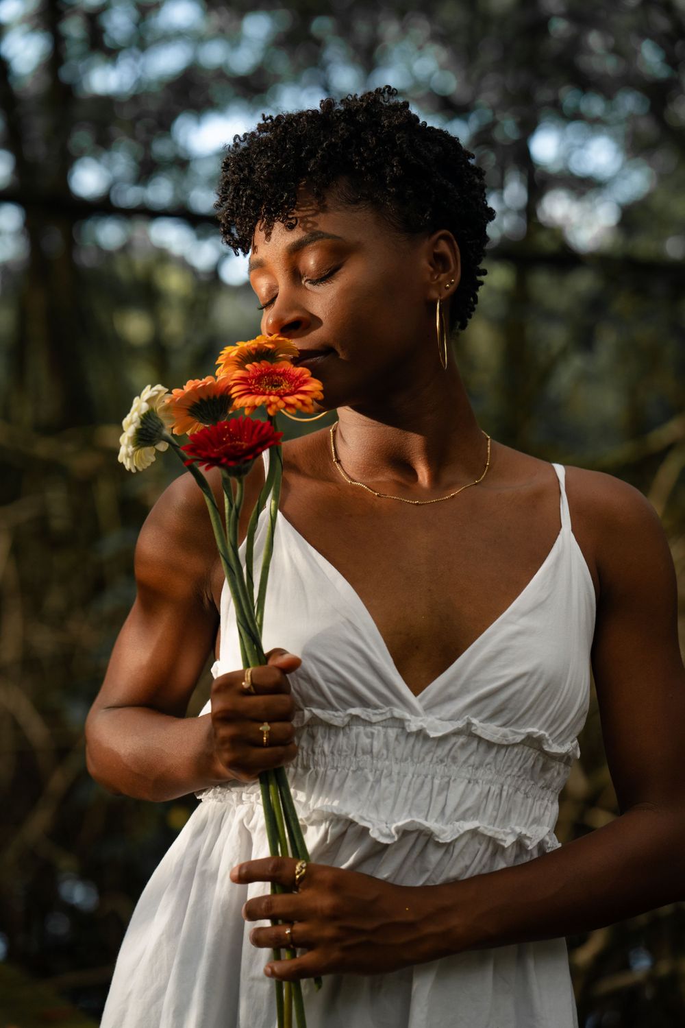 Femme en robe blanche tenant des fleurs rouges, séance portrait en extérieur en Guyane