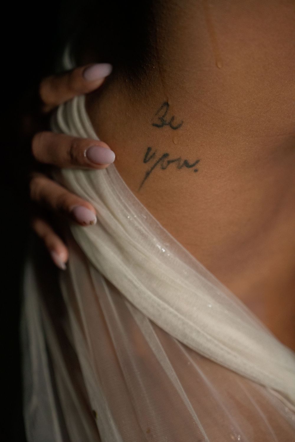 Détail d'un tatouage sur l'épaule sous un voile, portrait fine art