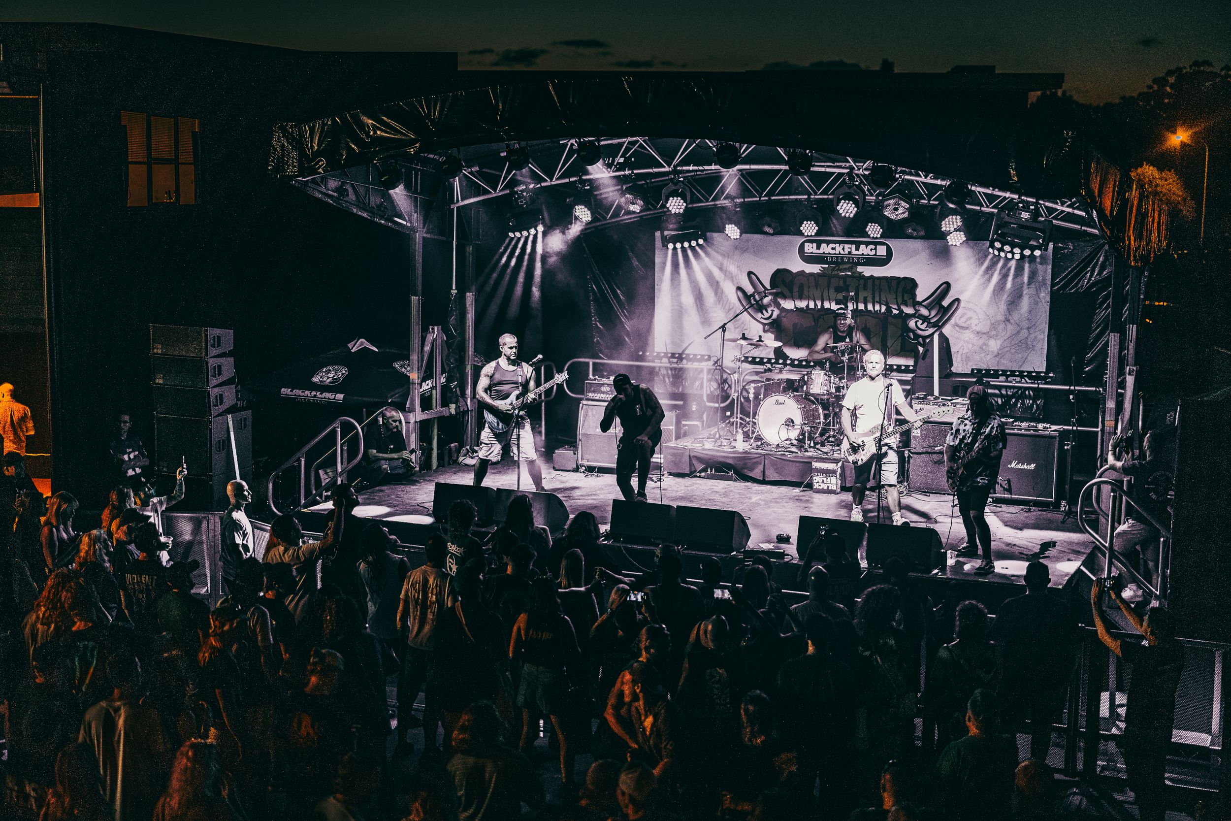 Band performing on stage with dramatic lighting and concert crowd during a live rock show.