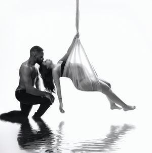 Artistic black and white photo of two dancers creating a graceful pose over reflective water surface.  luxury Vanessa Charlotte Photography