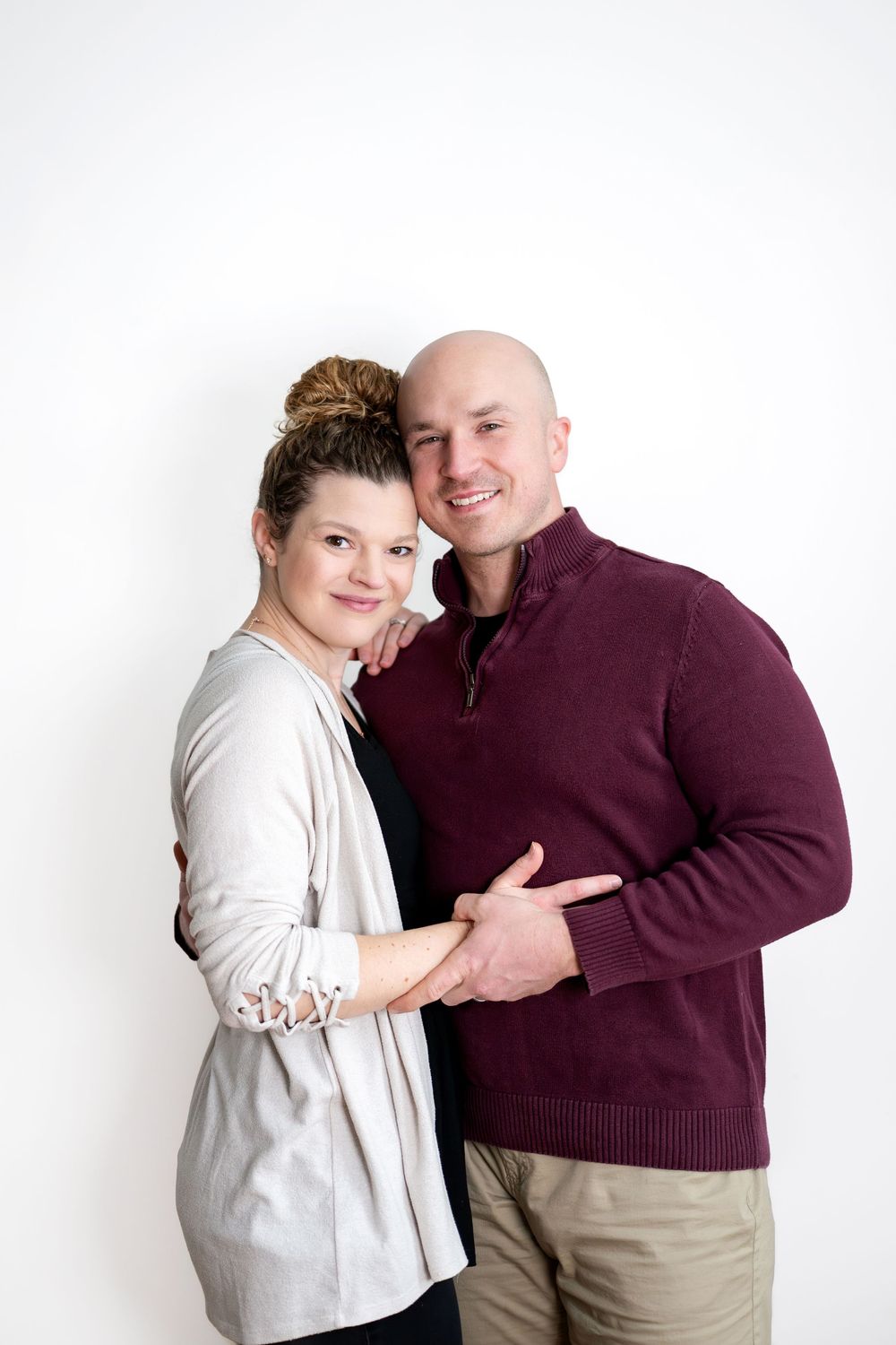 Smiling couple embracing warmly in a classic studio portrait against a white background.
