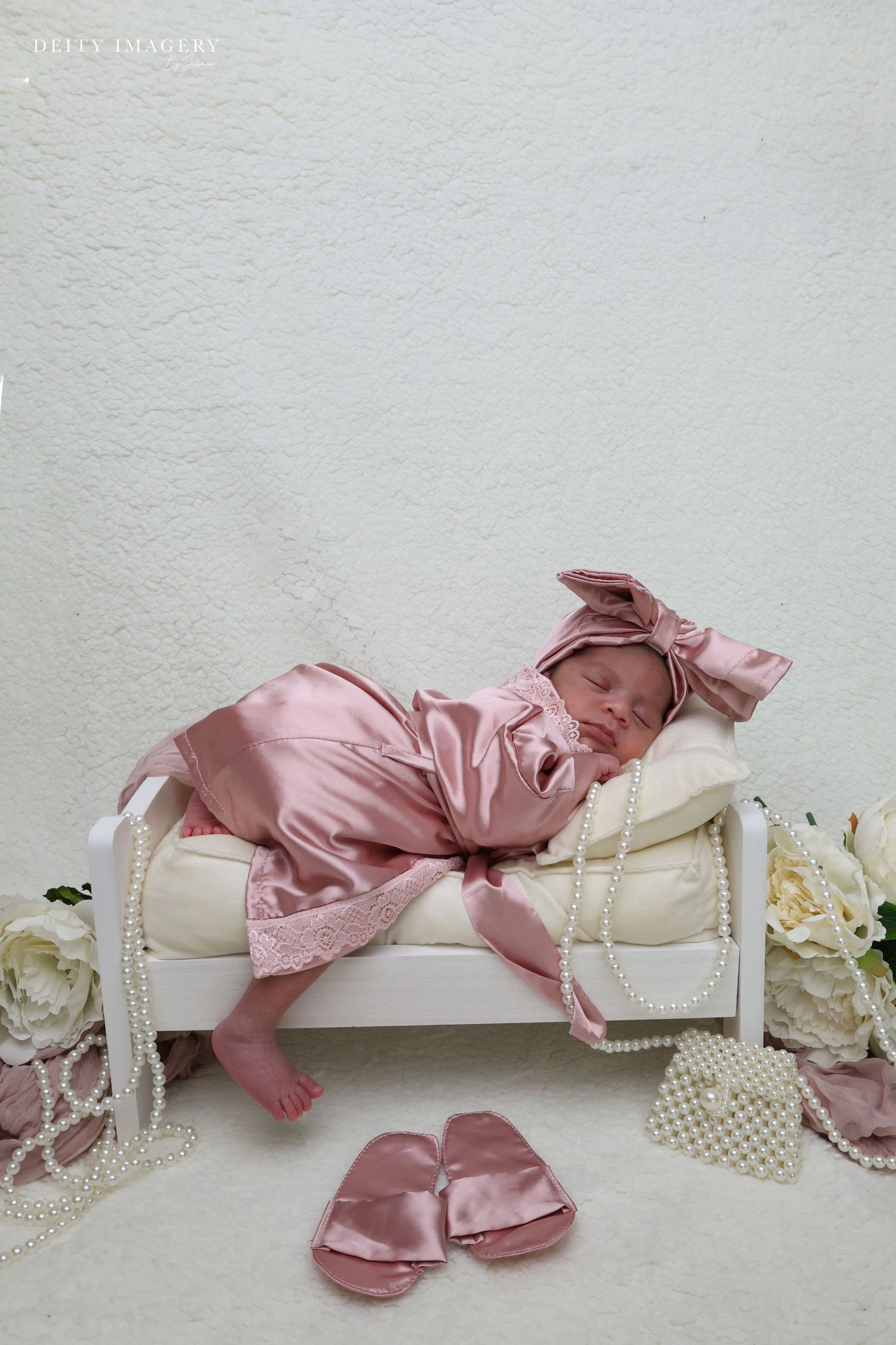 A pink silk ribbon elegantly drapes across a white textured surface creating a delicate composition.