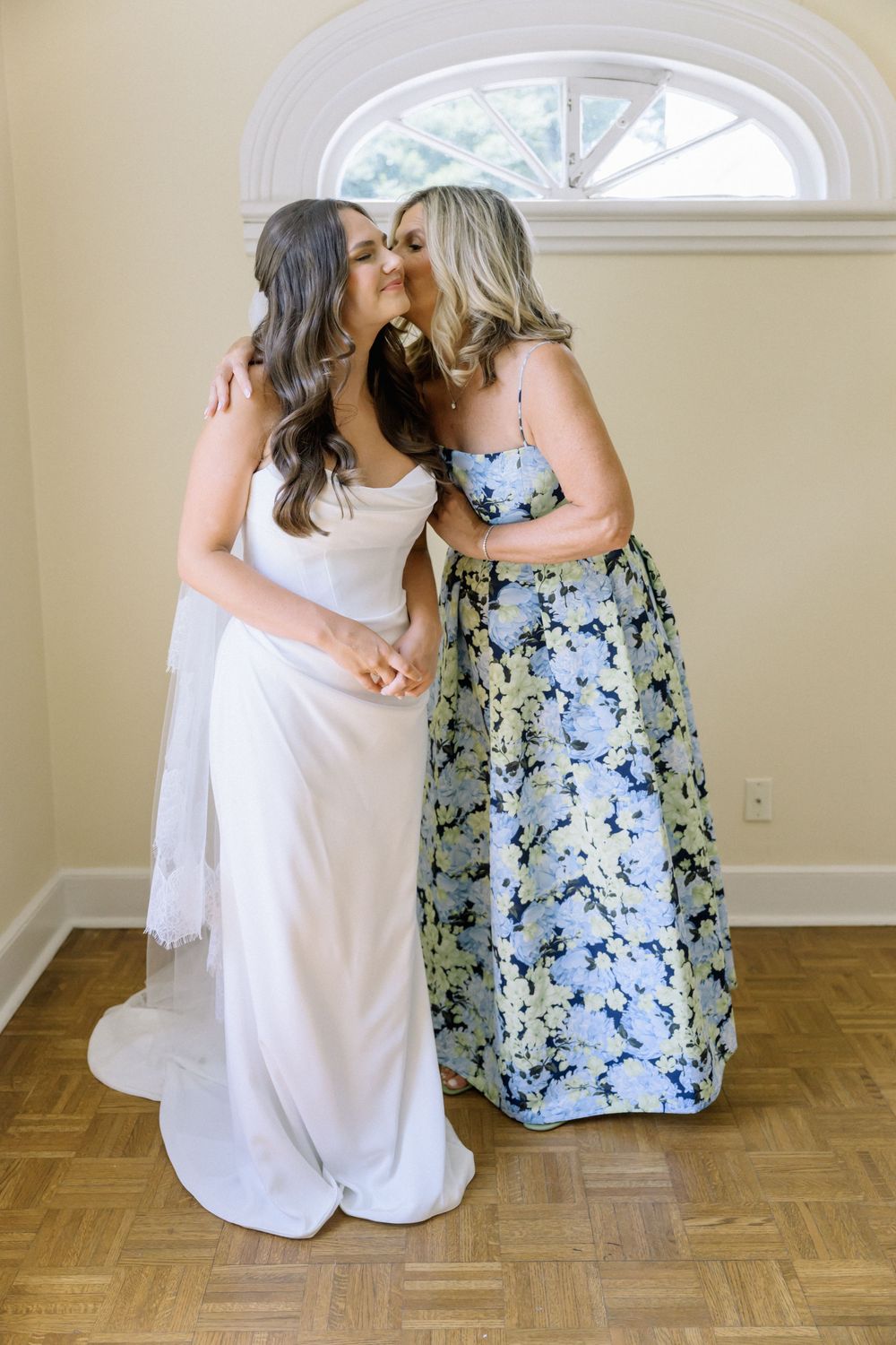 Wedding preparation series showing two people in white and floral dresses sitting on hardwood floor.