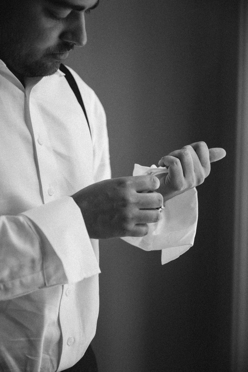 Black and white images of someone adjusting cufflinks and preparing formal attire.