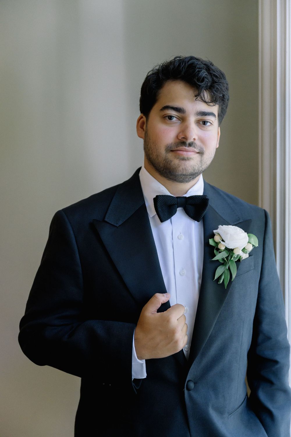 Close-up shots of a groom adjusting his bowtie and suit jacket before the ceremony.