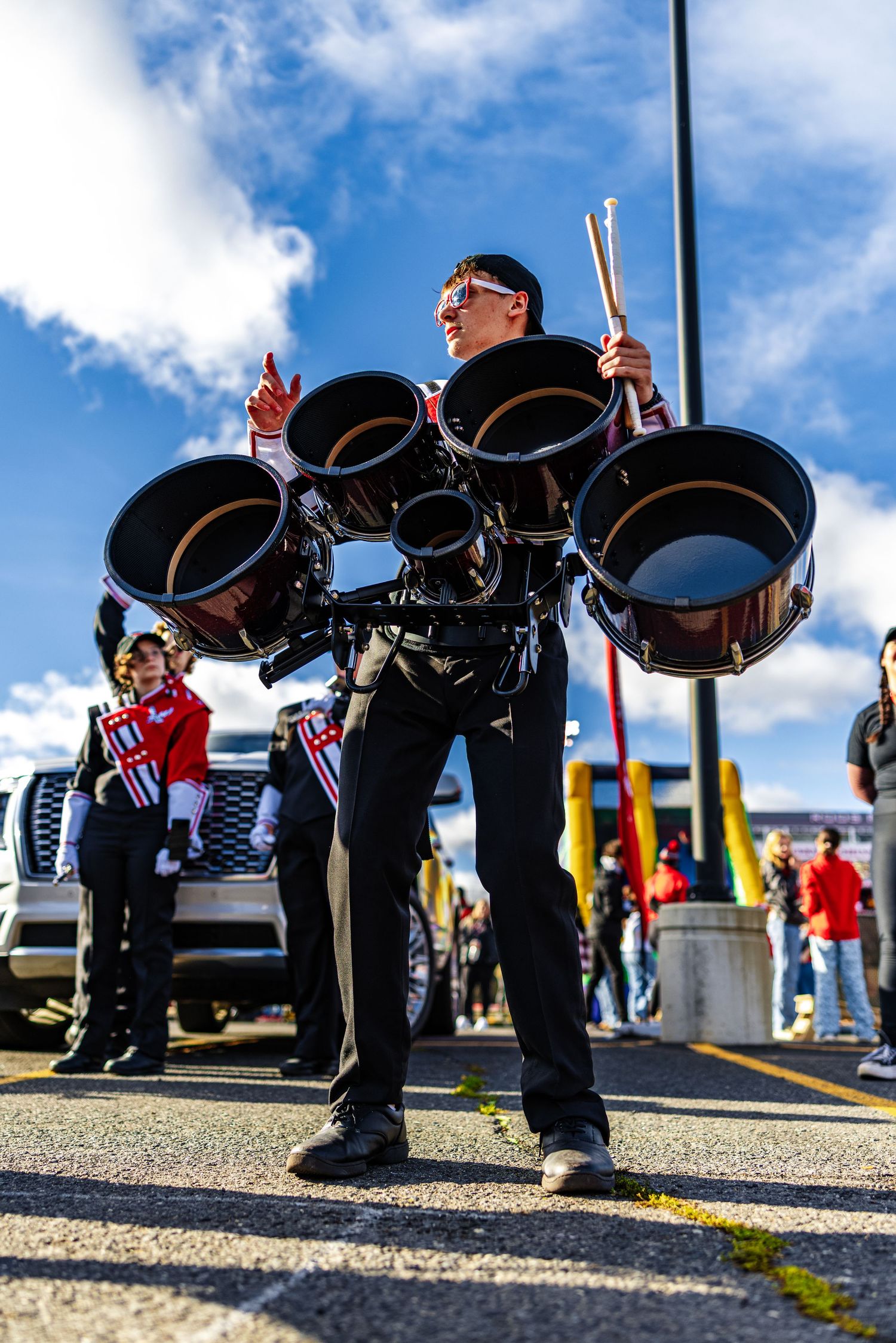 Low-angle view of a marching band lineup showing polished black shoes against pavement under blue skies.