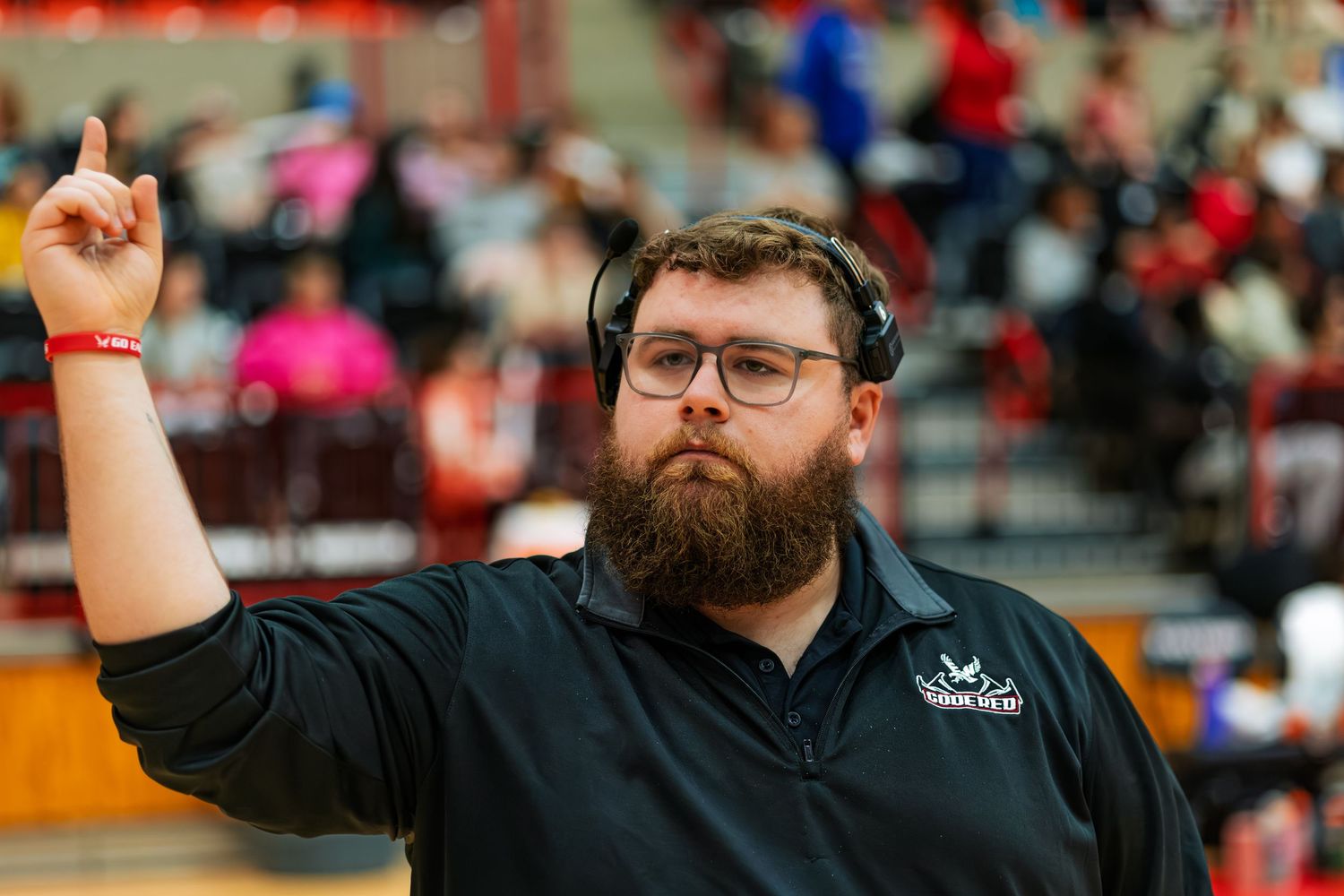 A band conductor signals a call with raised arms during a game.