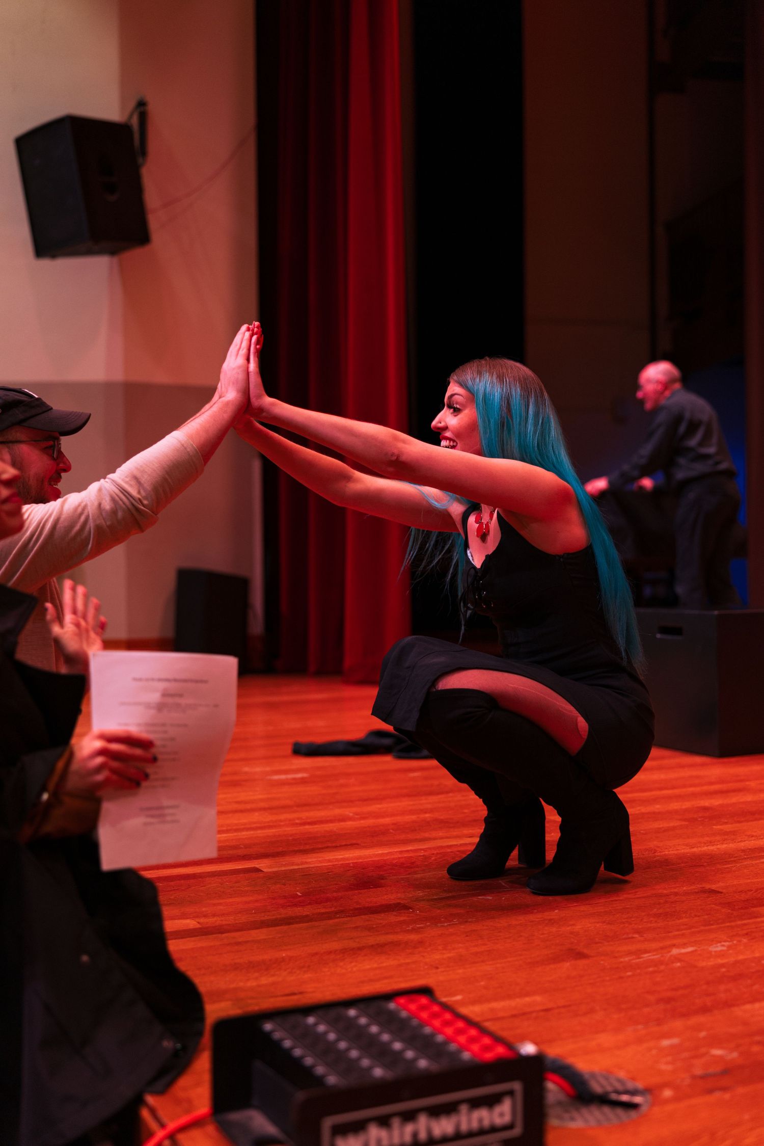 Singers perform a routine on a red-lit wooden stage during a contemporary vocal performance.