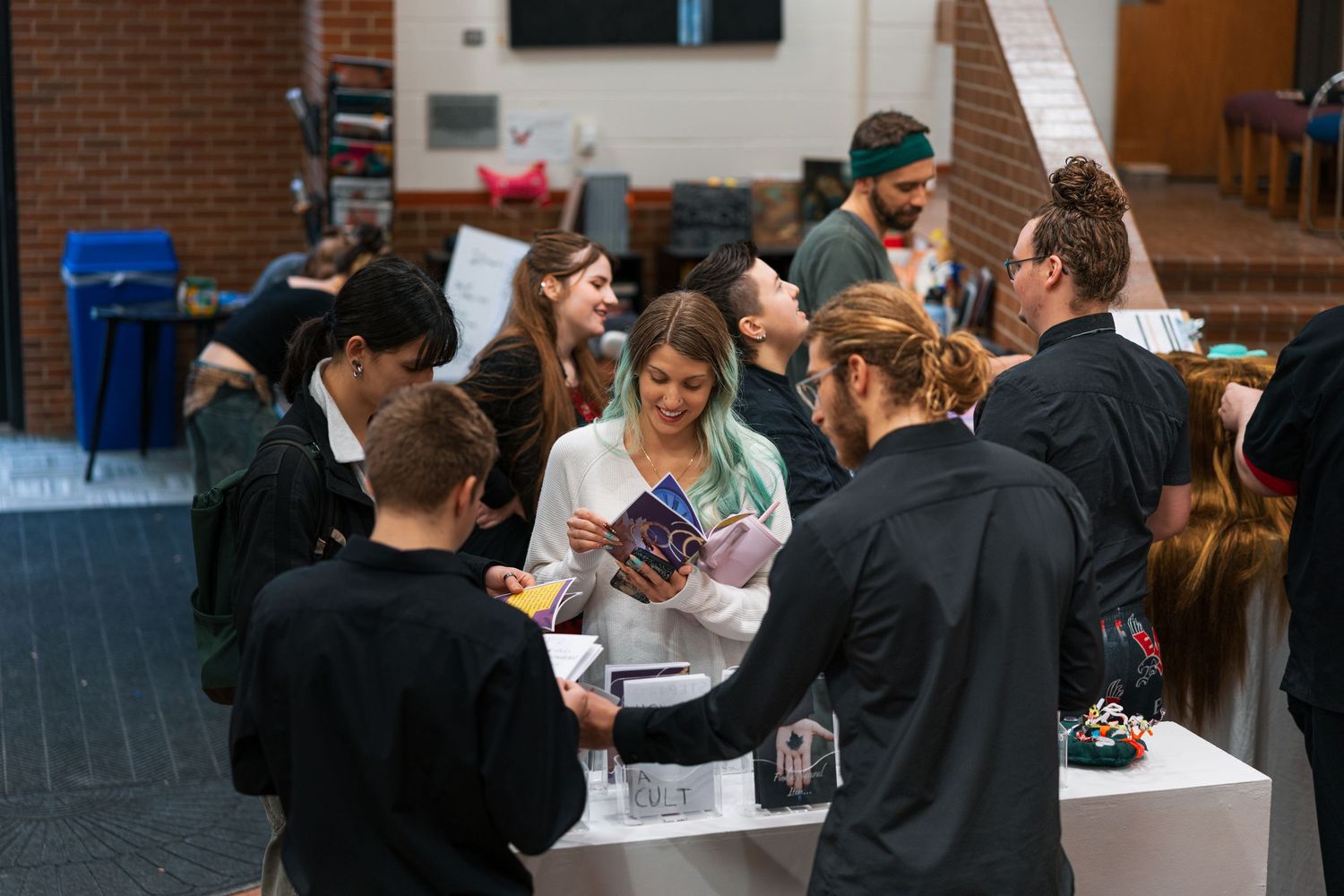 A crowd of people gathered in a brick-walled space participating in what appears to be a social event or gathering.