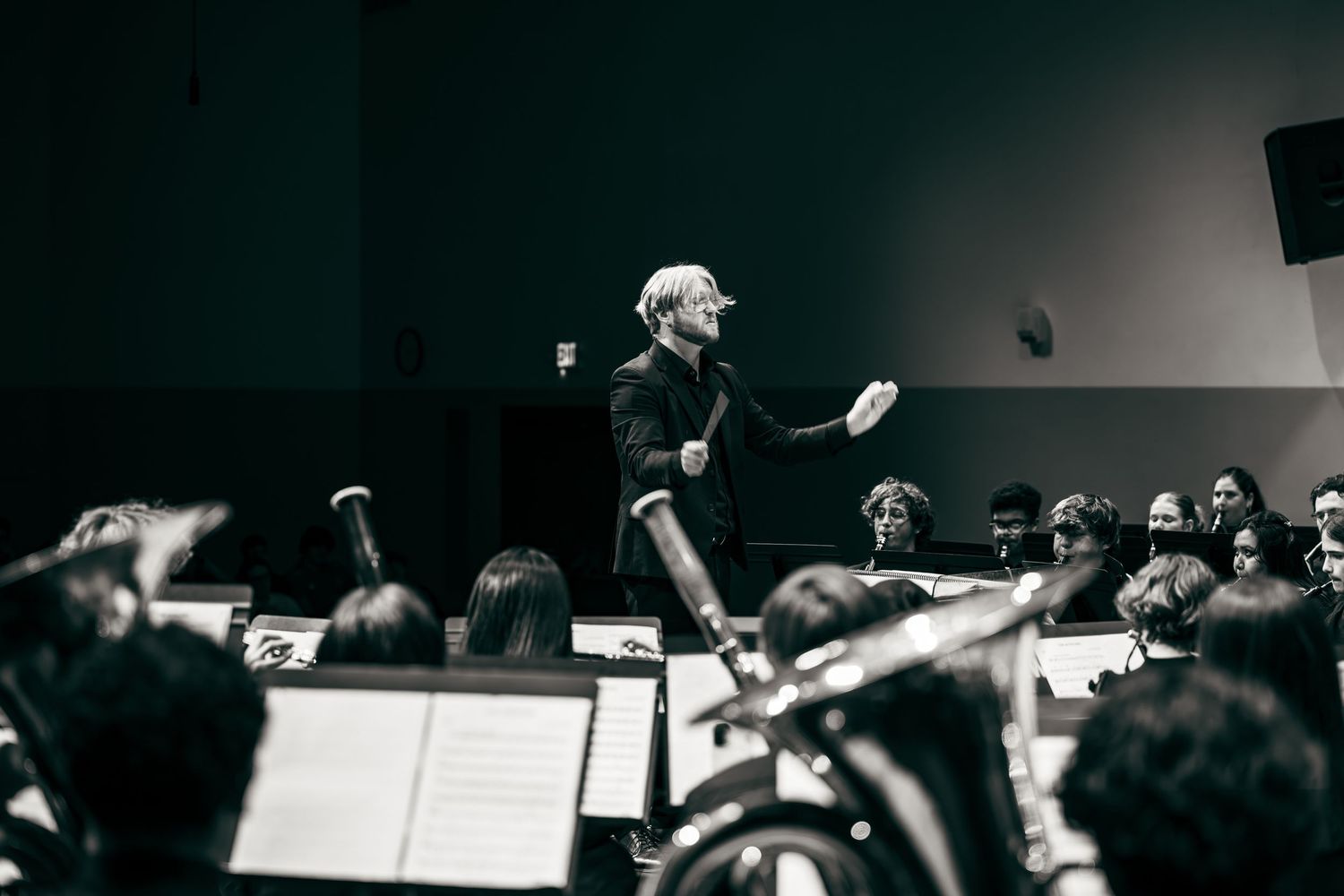 Black and white concert performance photos showing musicians and sheet music in a dark auditorium setting.