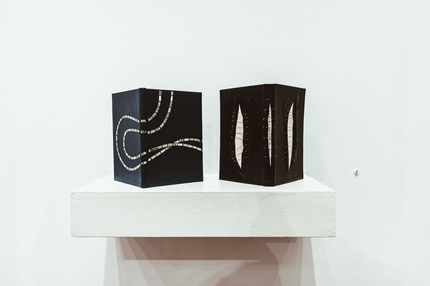Black and white decorative books with curved line patterns displayed in a row on a light background.