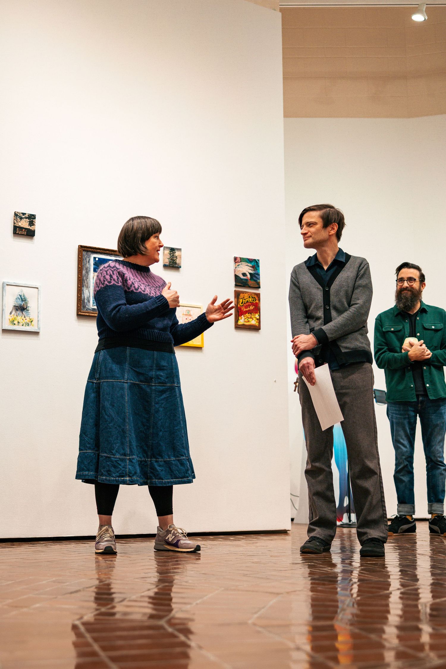 A sequence of five photos showing two people having an animated discussion in an art gallery space.
