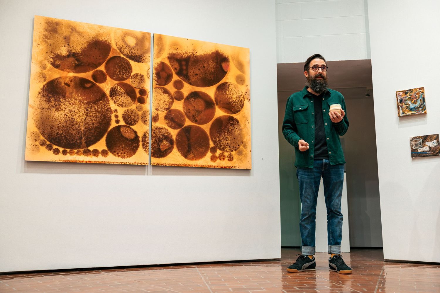 A series of photographs showing someone viewing circular rust-colored artwork installations in a white gallery space.