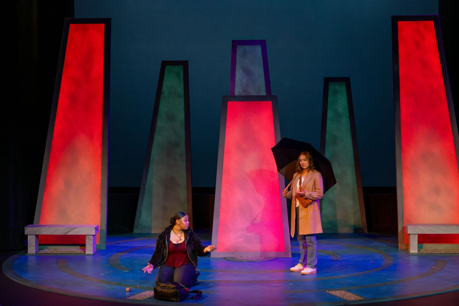 Performers on a colorfully lit stage with dramatic red and blue lighting create a theatrical scene.