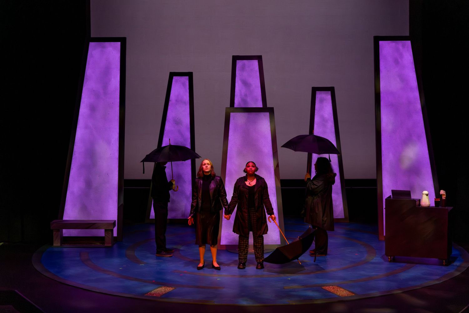 A sequence of theatrical stage scenes with purple lighting and silhouetted figures performing on a dark set.