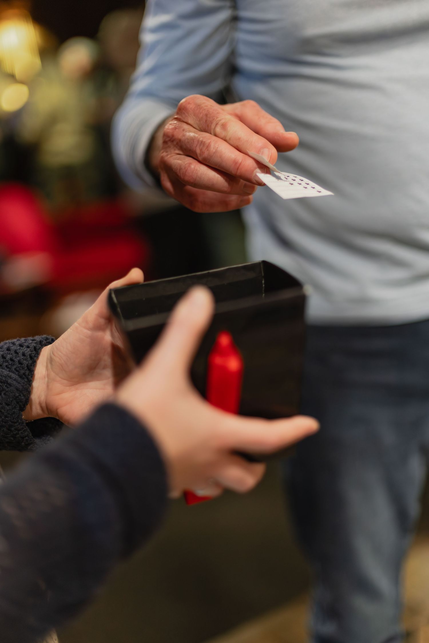 Close-up of hands exchanging a ticket into a black box at an event venue.