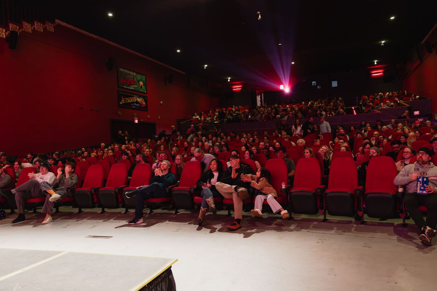 Large audience fills red-seated theater at a film festival screening event.
