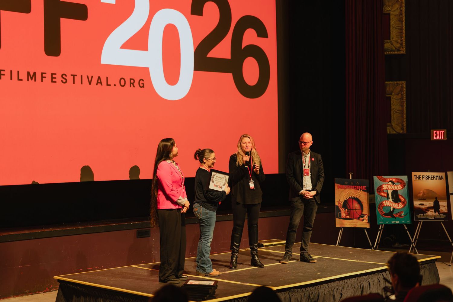 Award presentation ceremony on stage at SpIFF 2026 Spokane Film Festival with four people and film posters.