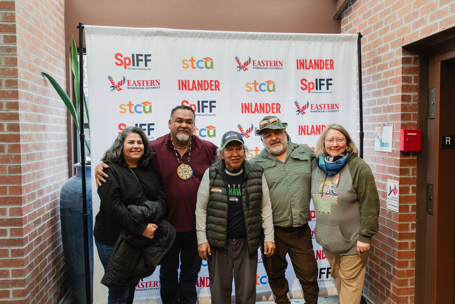 Five people posing together at SpIFF film festival step-and-repeat banner with sponsors.