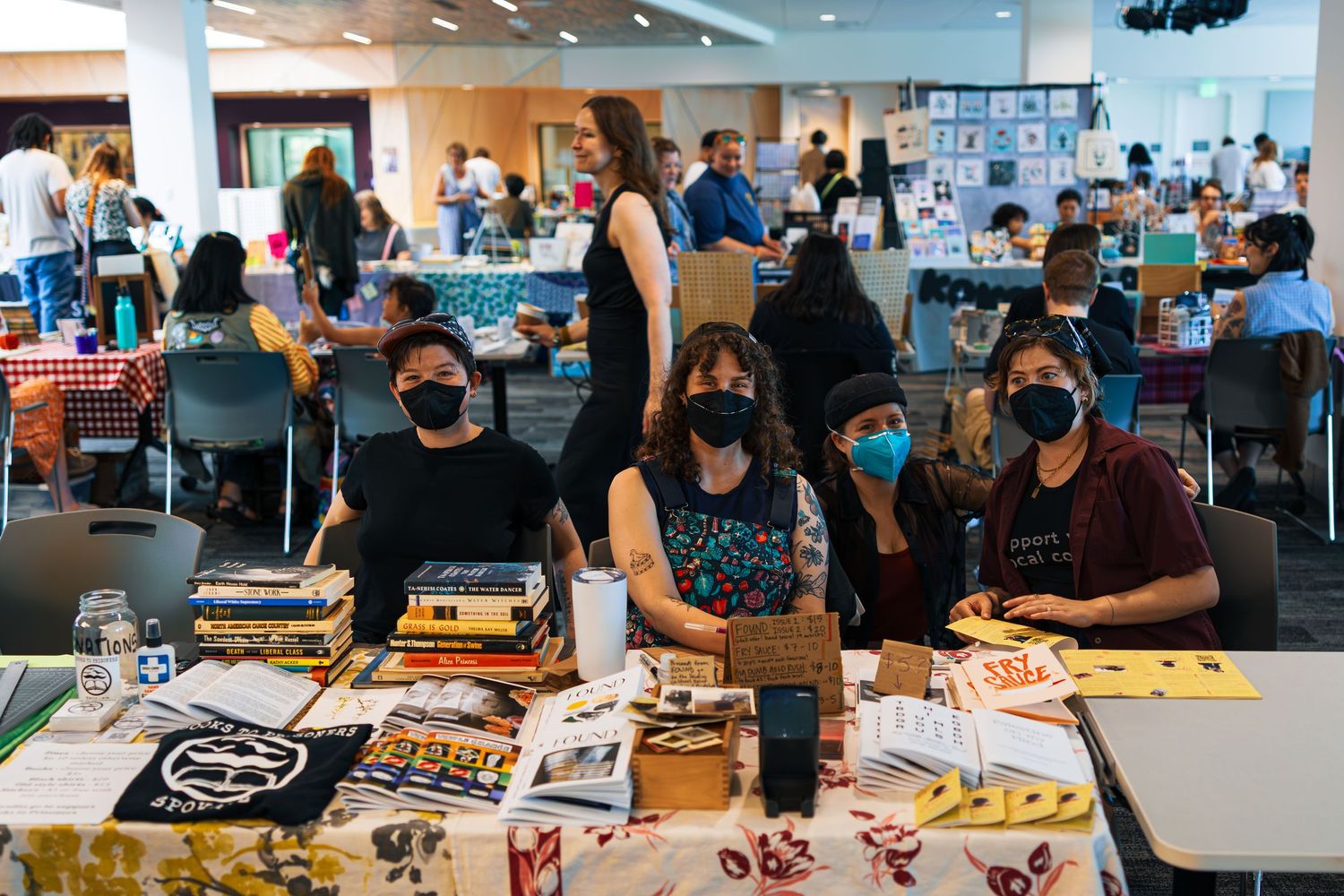 People gather around tables in a bright office space working on art and creative projects during a workshop session.