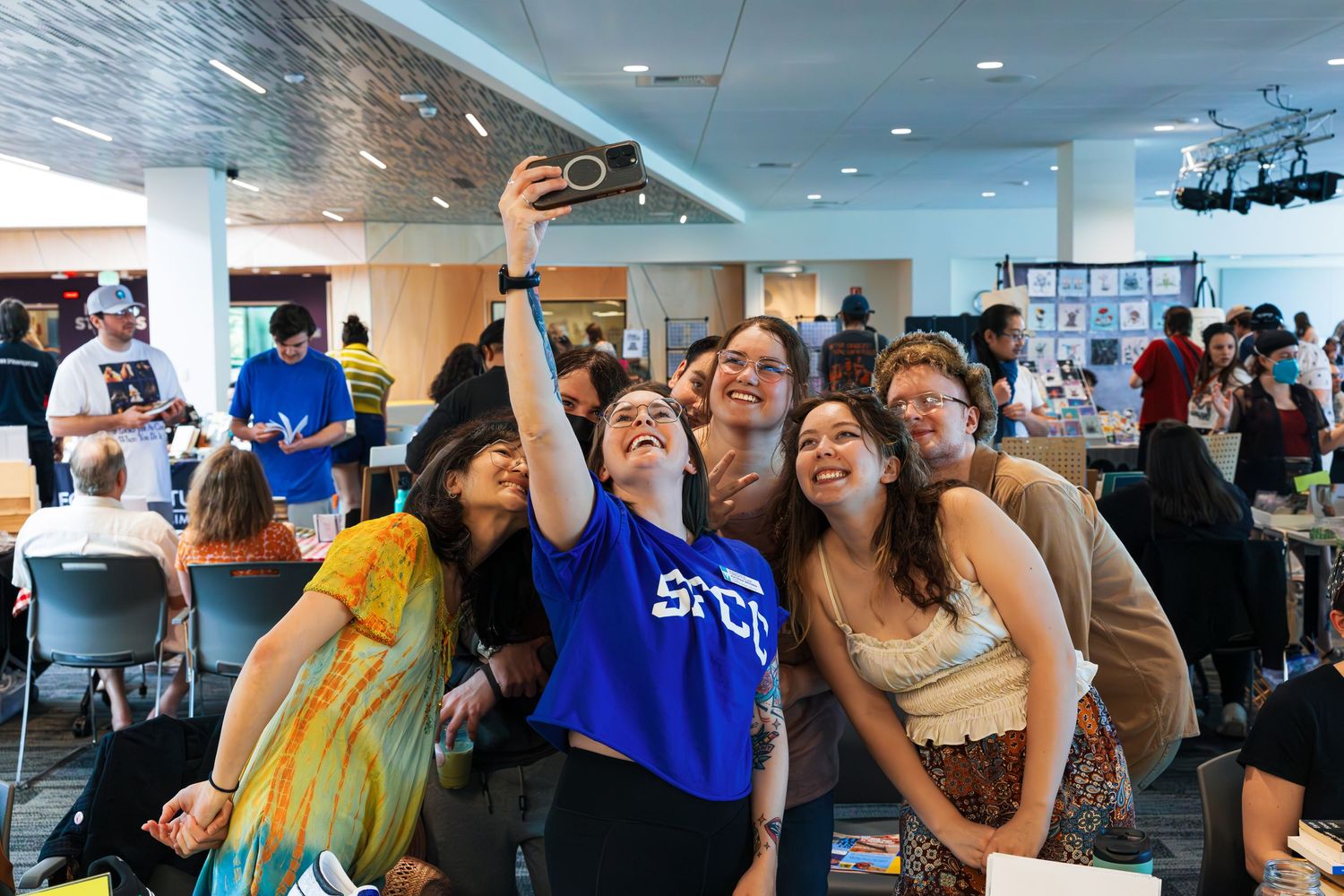 People gathered in an office space celebrate and cheer during what appears to be a group celebration or event.