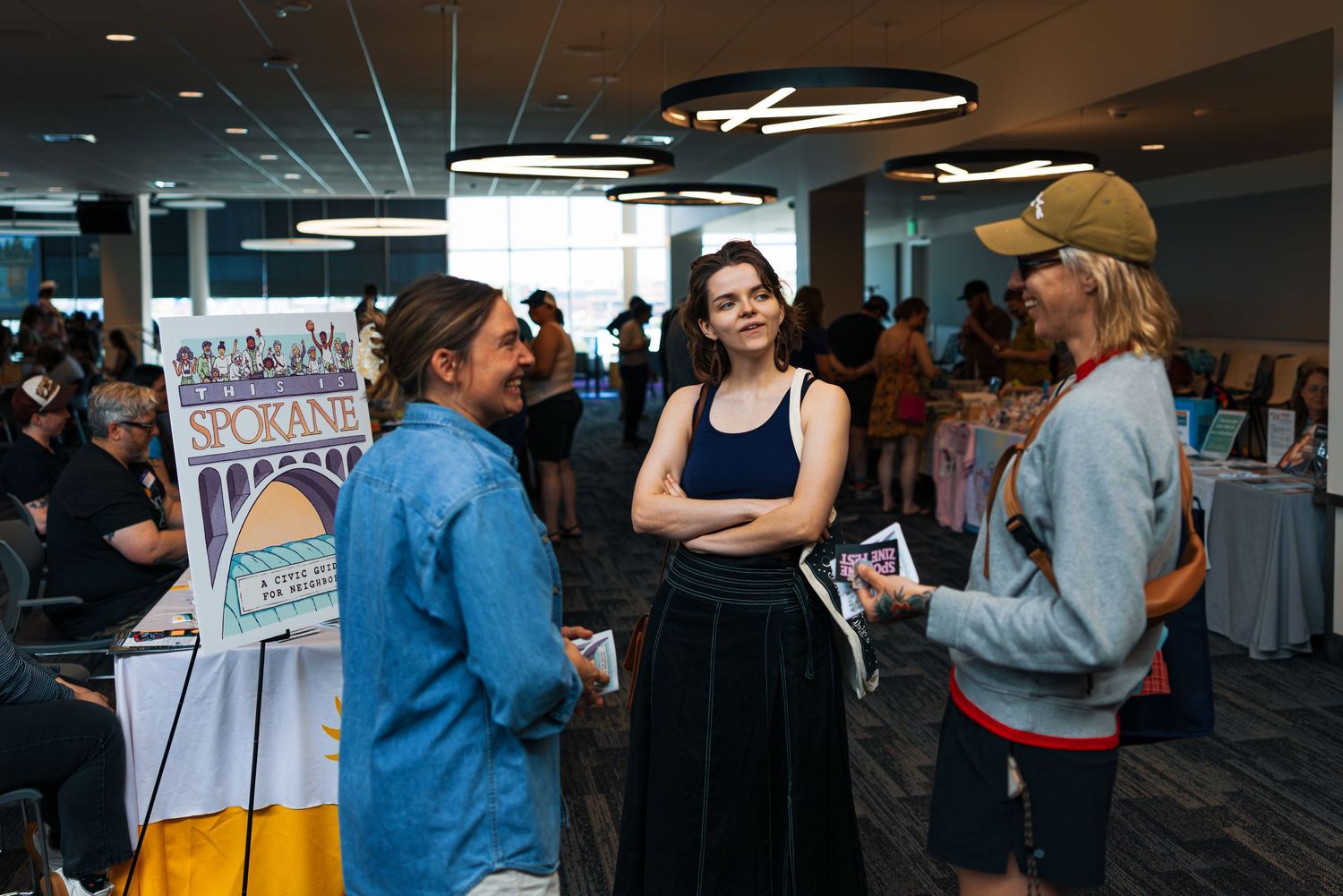 People gather and converse at an indoor event space with a banner visible in the background.