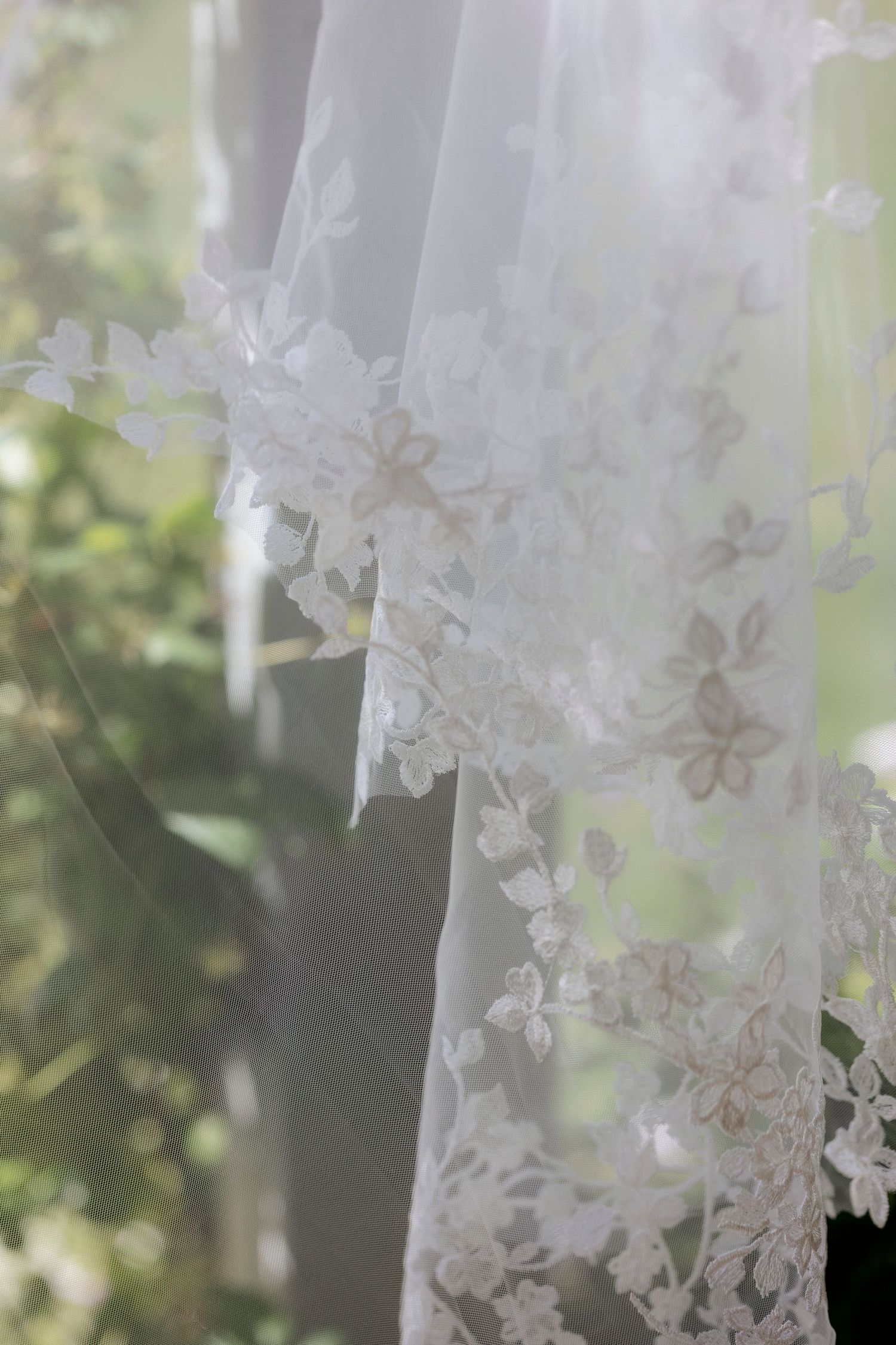 Delicate white lace bridal veil with floral patterns filtering sunlight att castle farms wedding venue