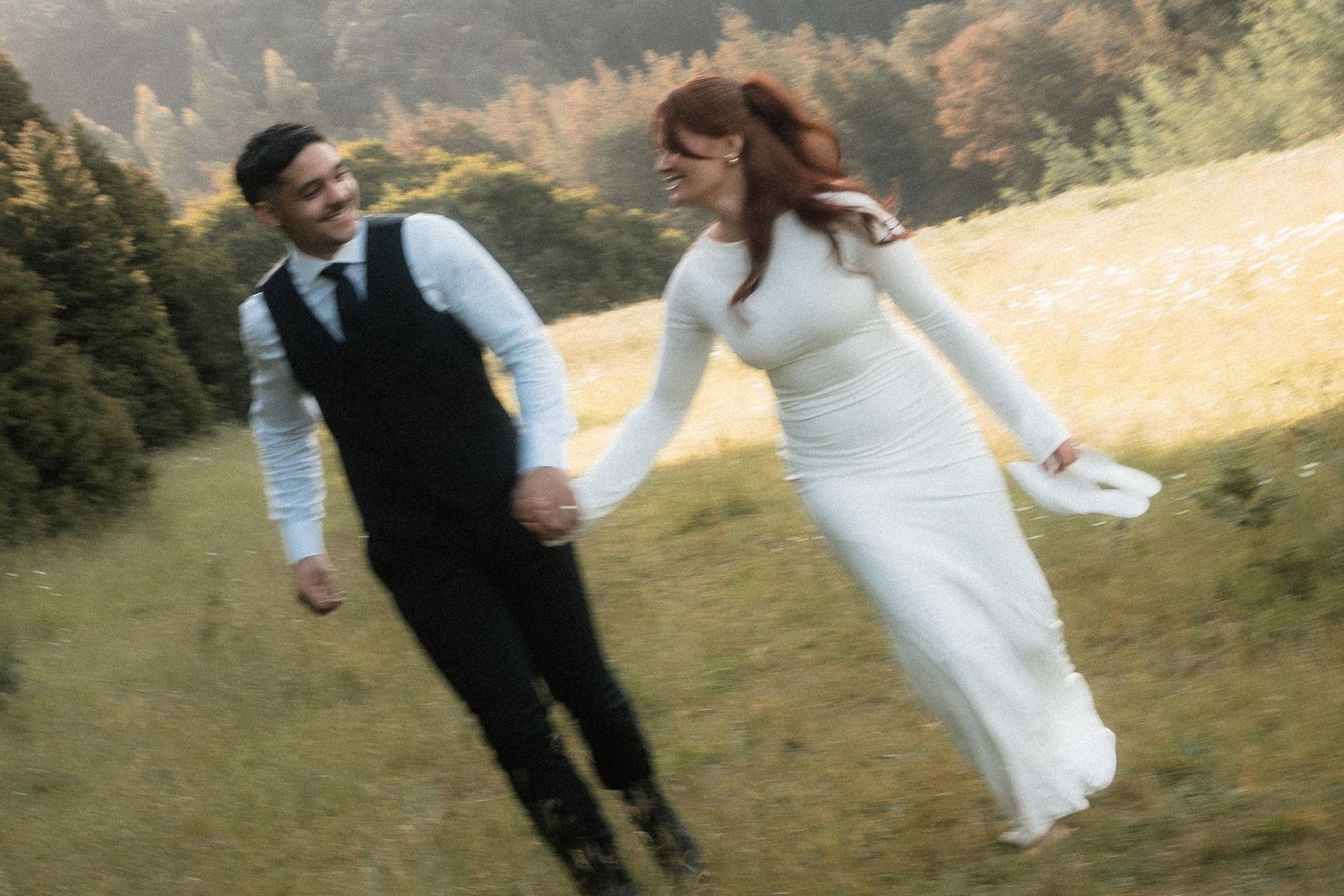 A couple dances together in an outdoor meadow with mountains in the background during a wedding celebration at RJ Hamer, Olinda