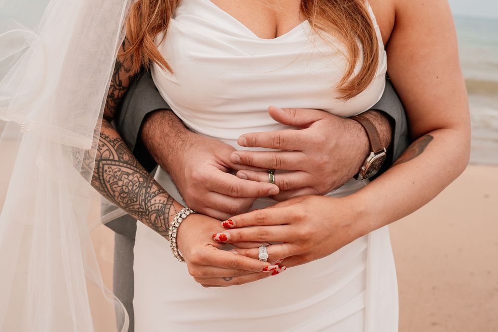 Close-up shots of hands resting on a white dress showing wedding and engagement rings.
