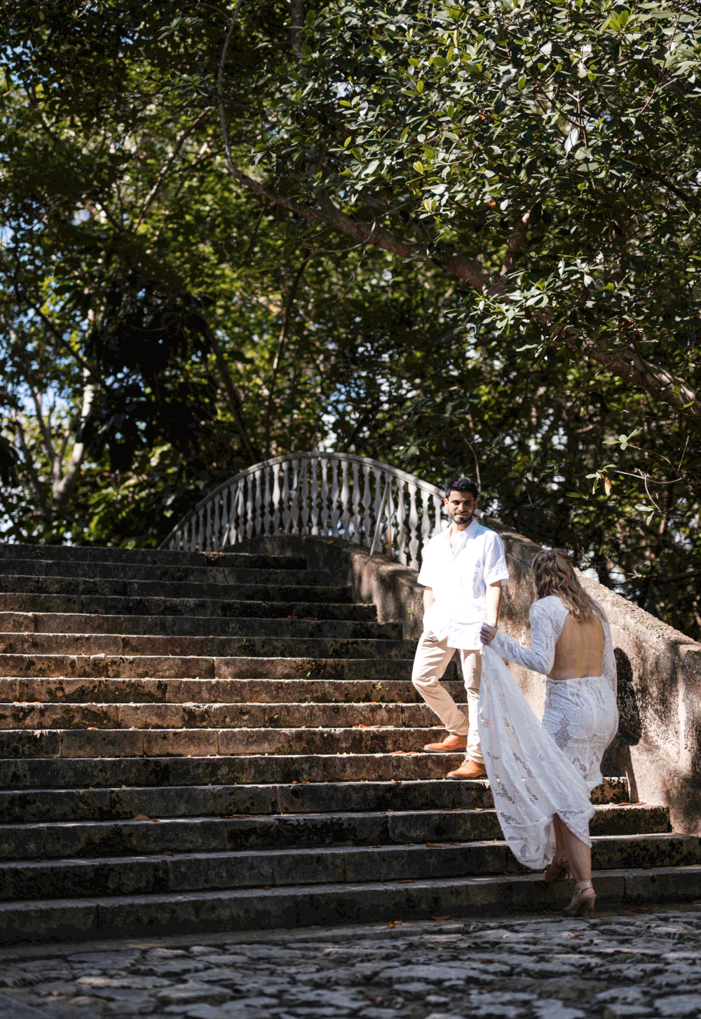 Couple walking together through garden steps during engagement session at Vizcaya