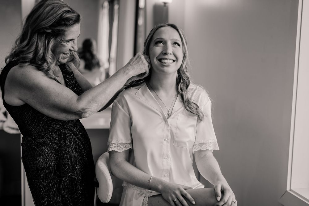 Wedding party getting ready in a bright room with natural light and joyful expressions.