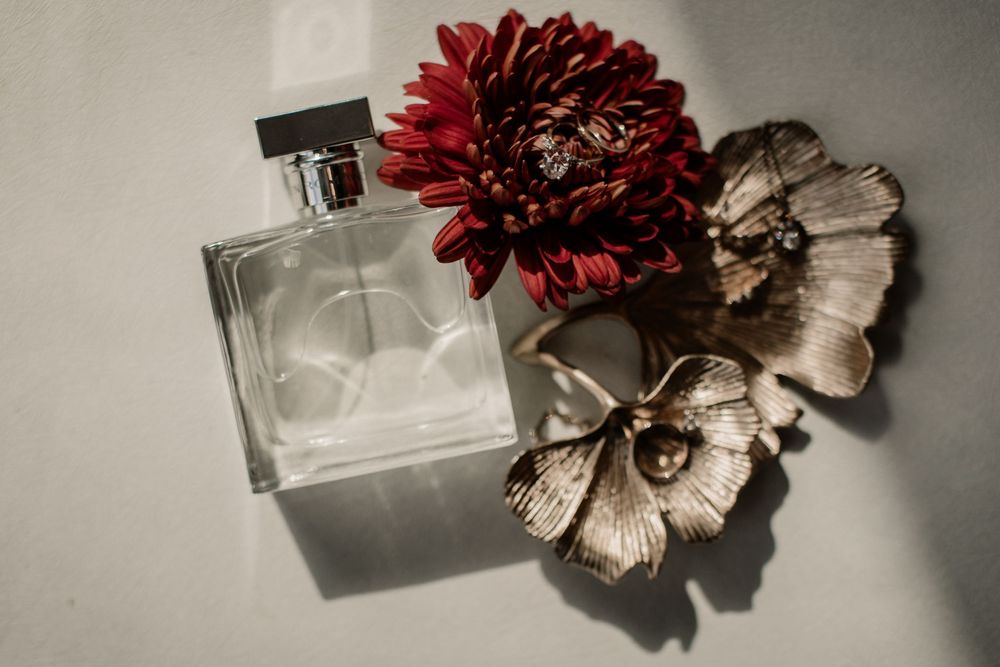 Artistic still life of red flowers and perfume bottle on grey background.