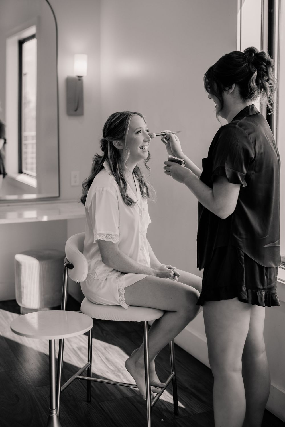 A series of black and white photos showing wedding preparation moments in a bright room.