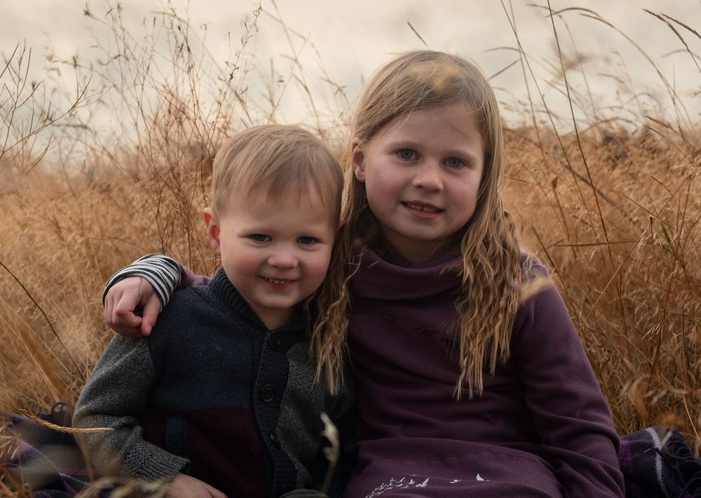 Intimate family portrait session in a field of dried grass at dusk.