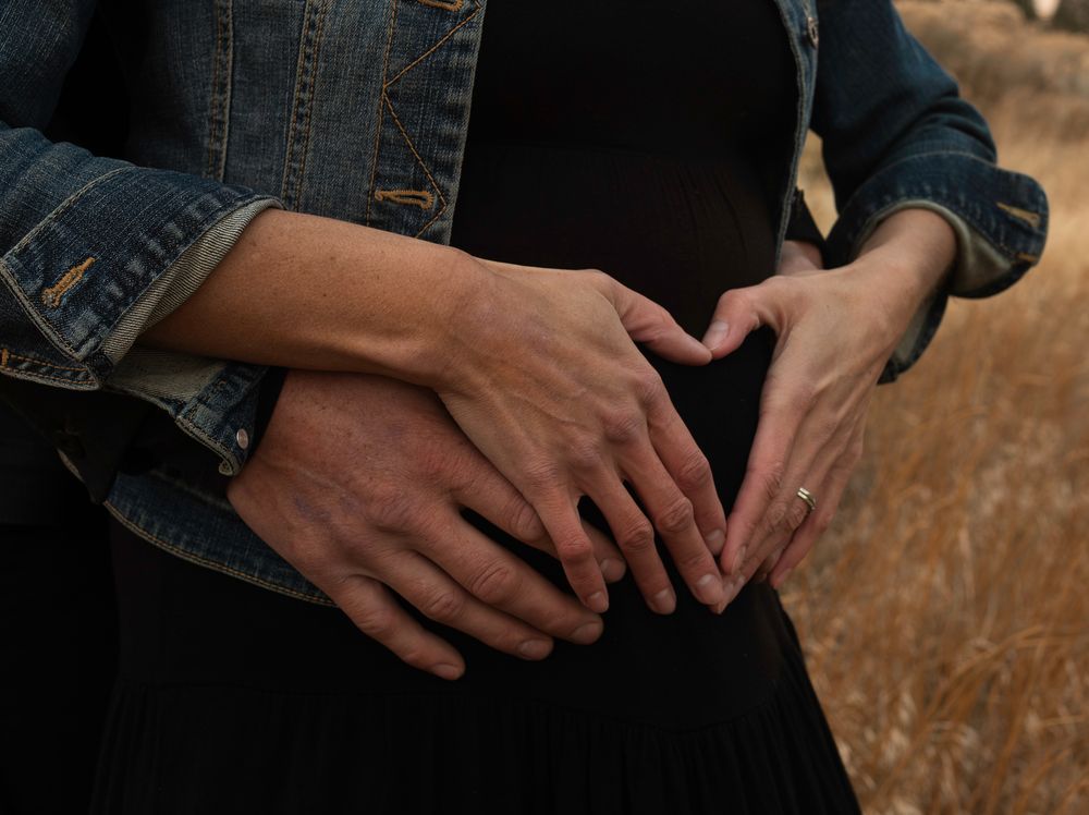 Close-up details of hands and denim jacket during outdoor photo session.