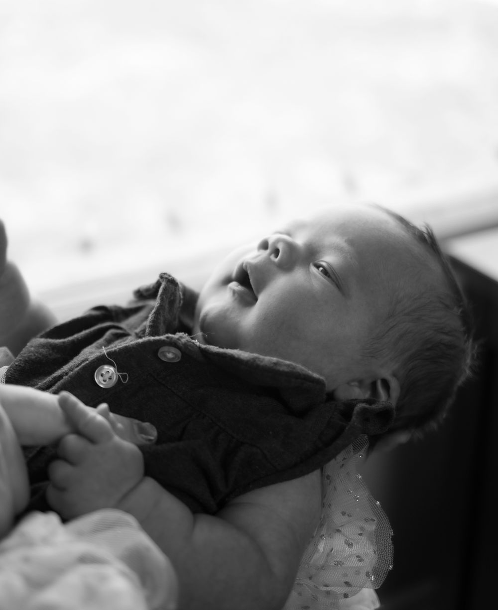 Black and white close-up series of sleeping newborn on dark fabric.