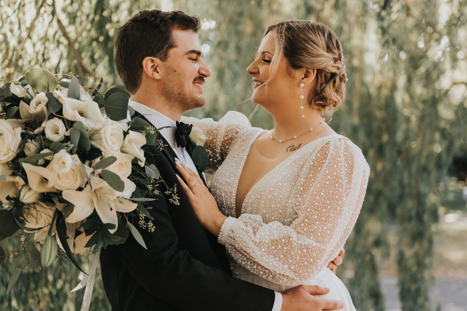 Romantic wedding couple embraces outdoors with soft lighting and floral arrangements in an ethereal garden setting.