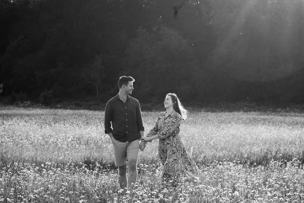 Couple walking through a blooming wildflower meadow in black and white photography.