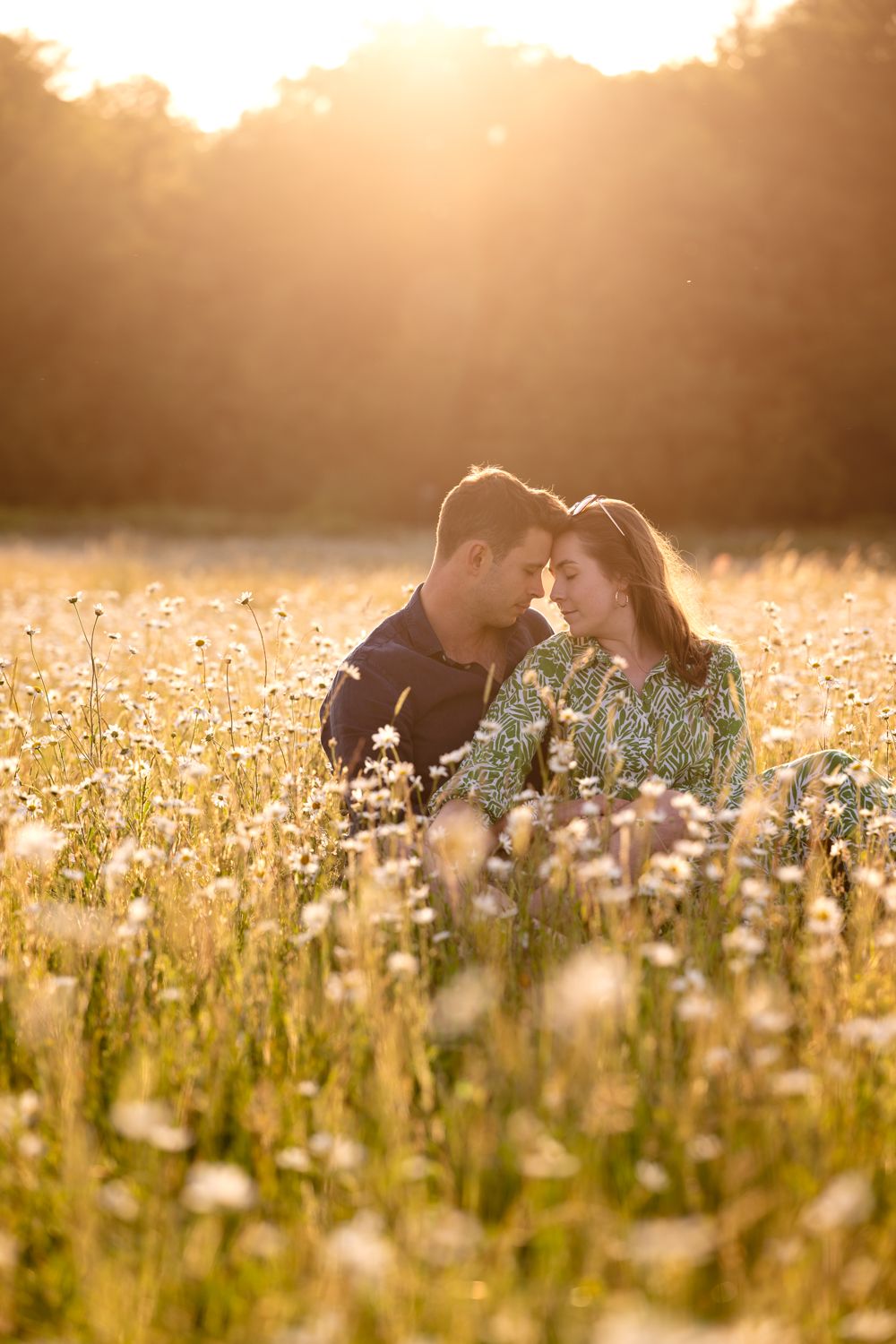 A couple shares an intimate moment in a sunlit meadow of wildflowers during golden hour.
