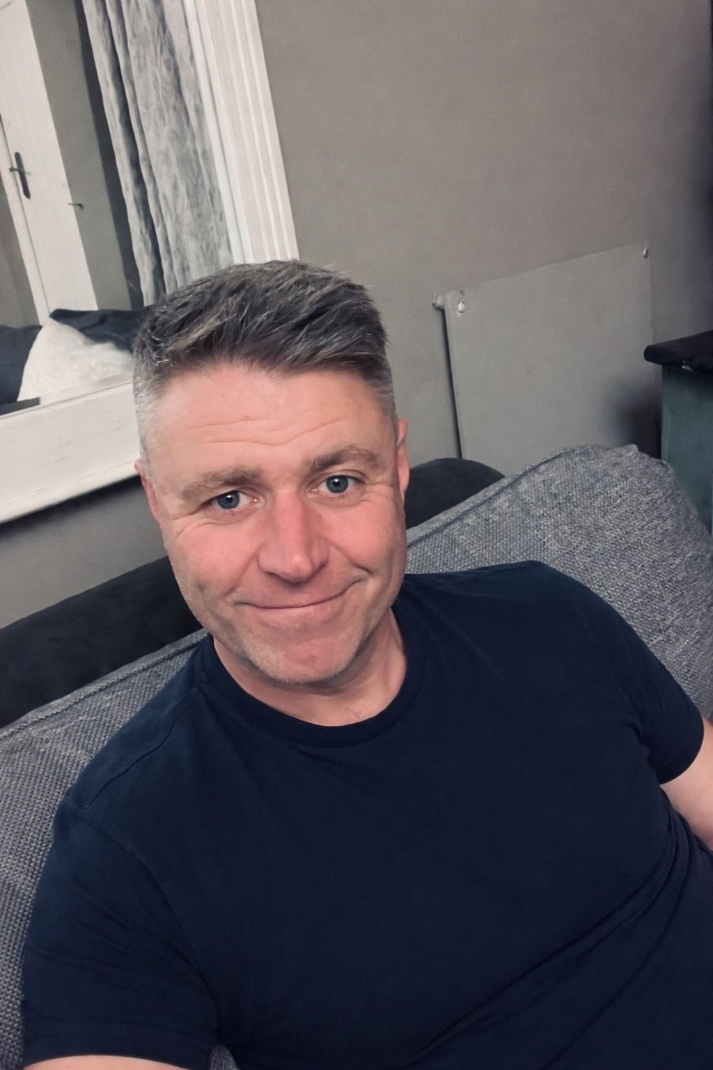 A series of selfie photos showing someone wearing a black t-shirt against a light colored wall background.