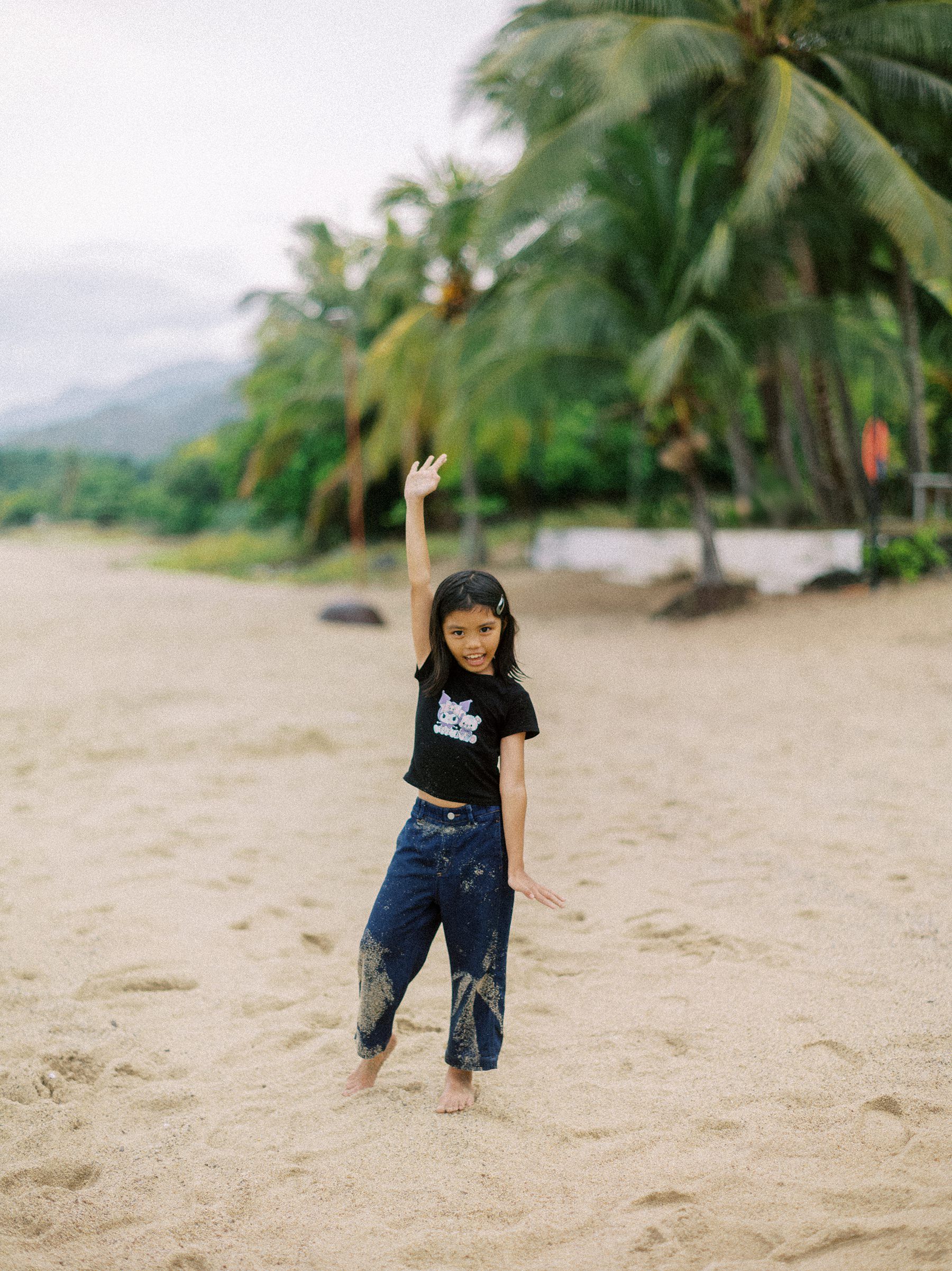 Child playing and running on a tropical beach with palm trees.