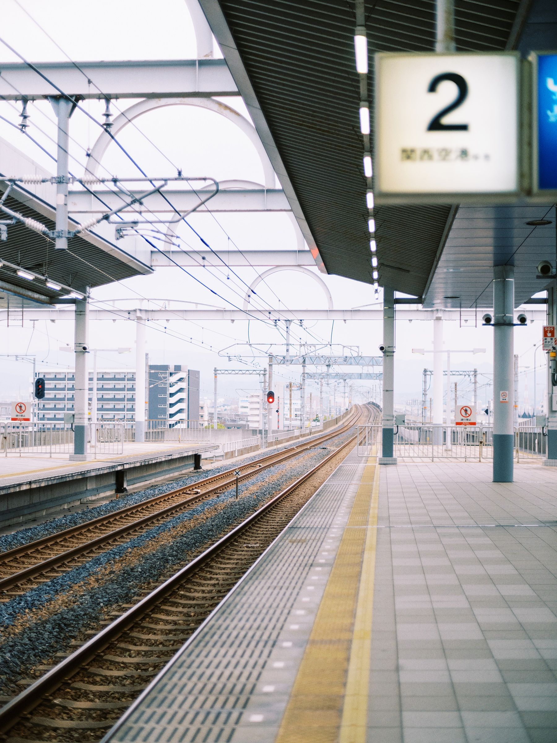 Empty modern train platform with number 2 sign and parallel tracks stretching into the distance.