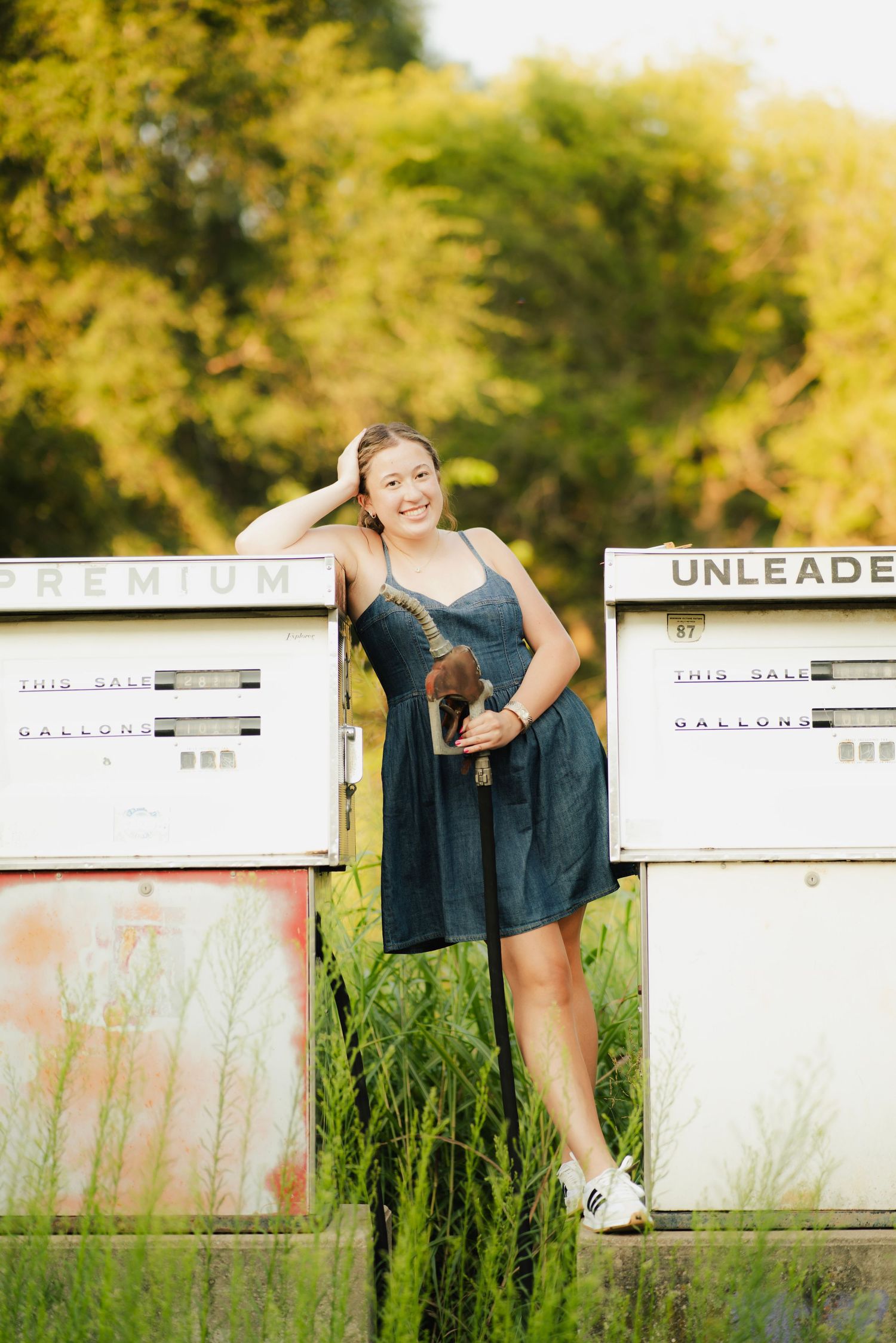 Young blonde woman in white crop top and jeans smells a bouquet of pink and blue roses outdoors.