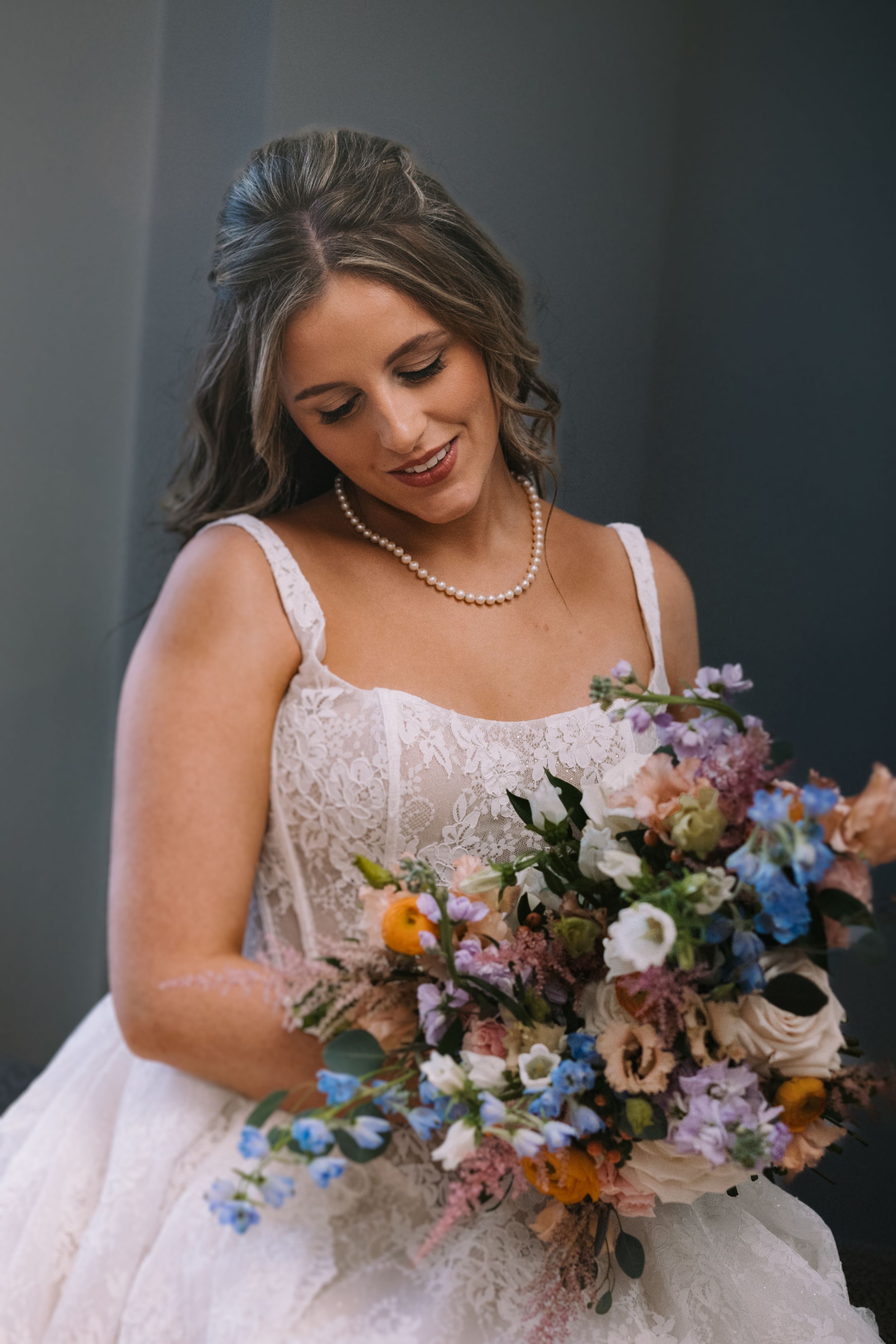 Close-up shots of a bride holding a vibrant bouquet with blue, pink and orange flowers.