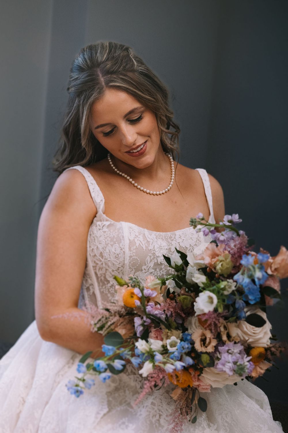 Close-up shots of a bride holding a vibrant bouquet with blue, pink and orange flowers.
