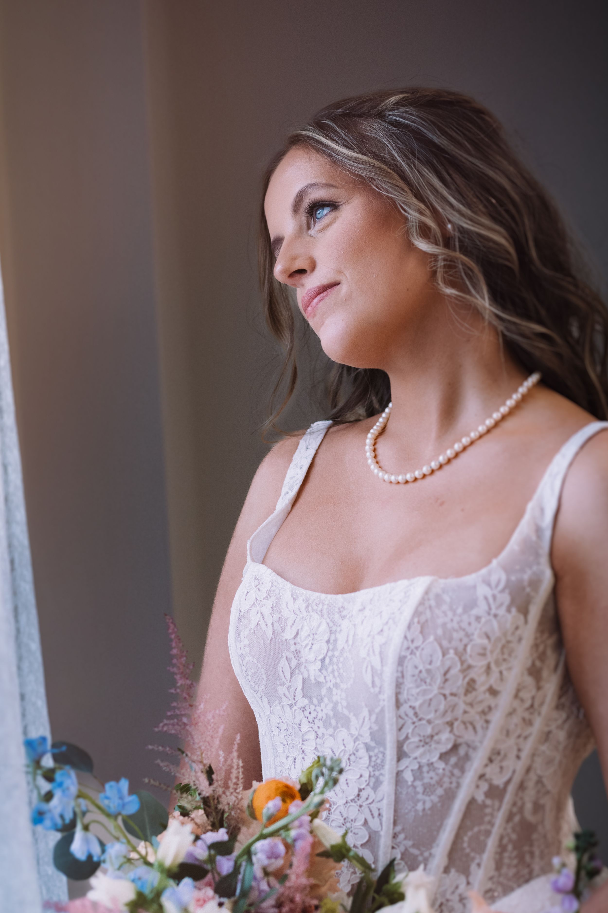 Artistic bridal portraits featuring a lace dress and pearl necklace against a dark background.