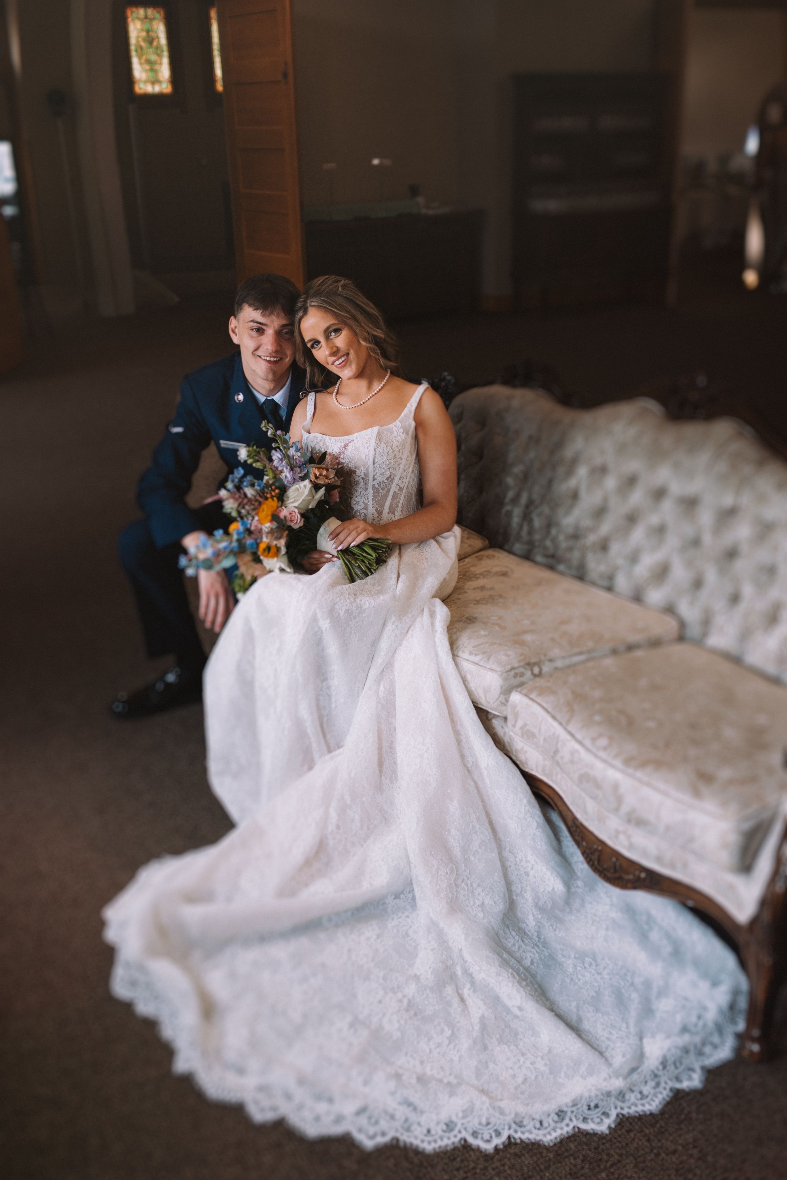 Wedding photos on a tufted couch showing romantic moments and a flowing lace gown.